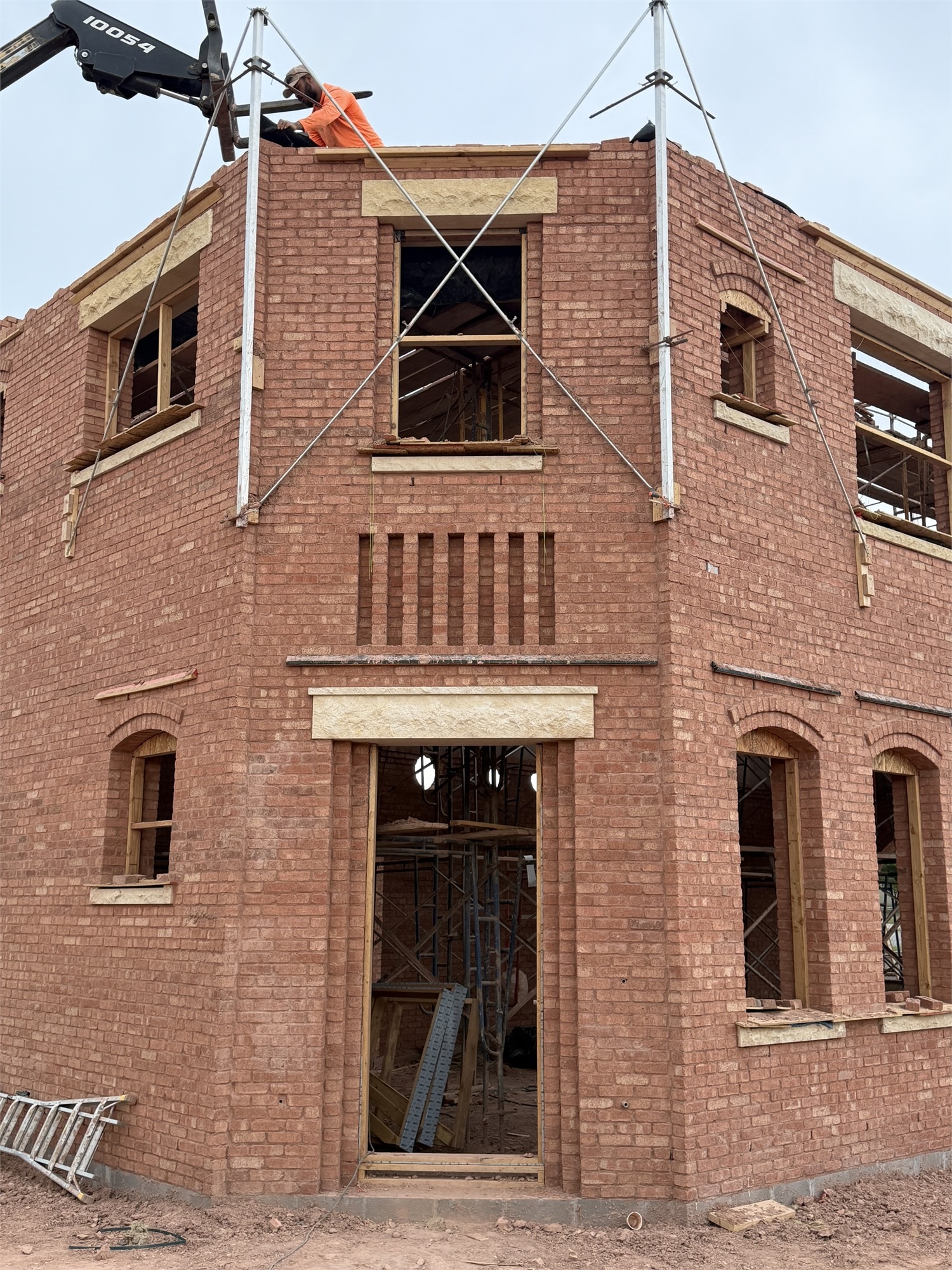 Apollo Workspace under construction — two-story brick building with workers on the roof, scaffolding visible.