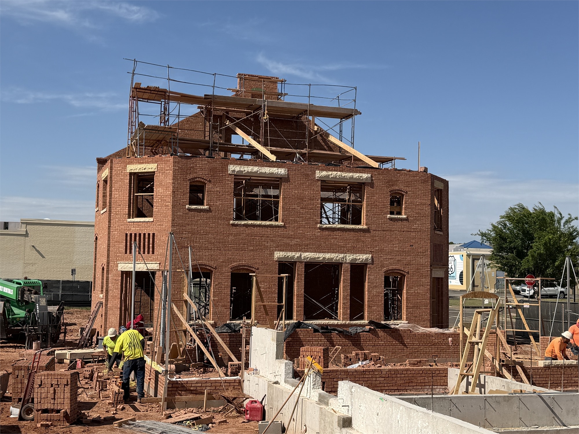 Wider view of Apollo Workspace mid-construction — brick walls erected, scaffolding around the roof line.