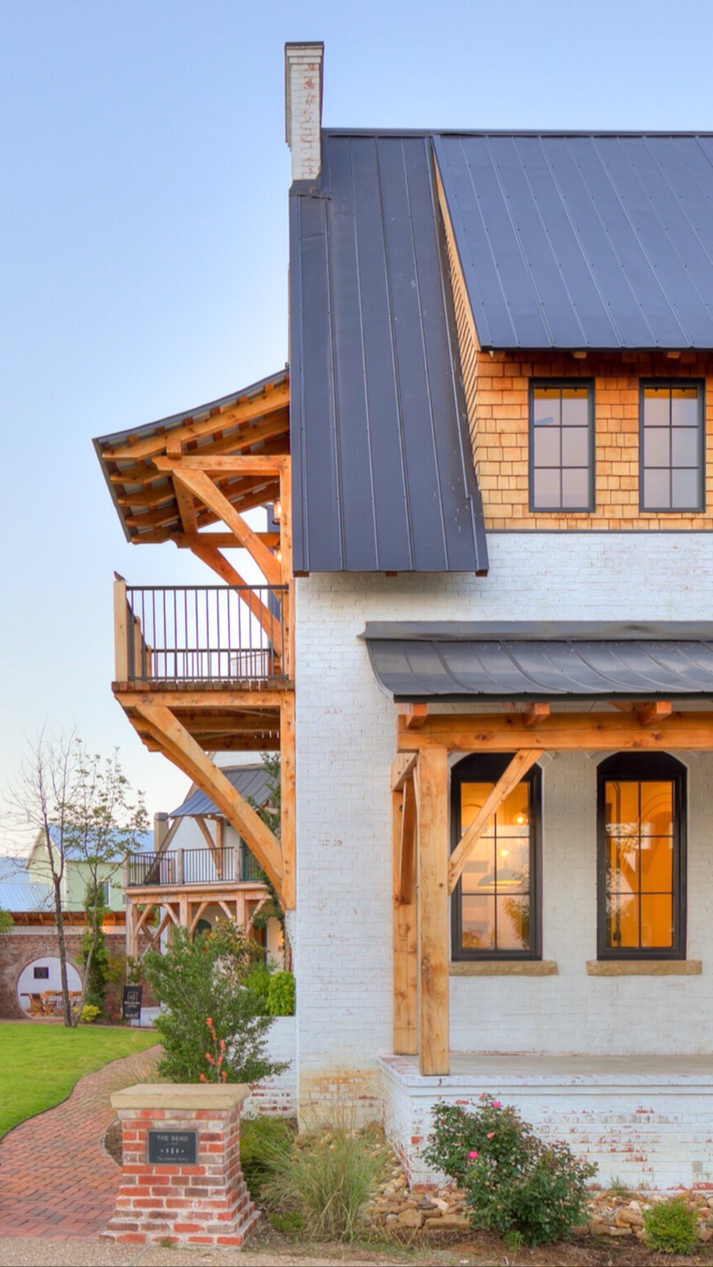 Exterior of a finished home at The Bend at Carlton Landing — exposed timber-frame brackets, painted brick, dark metal roof.