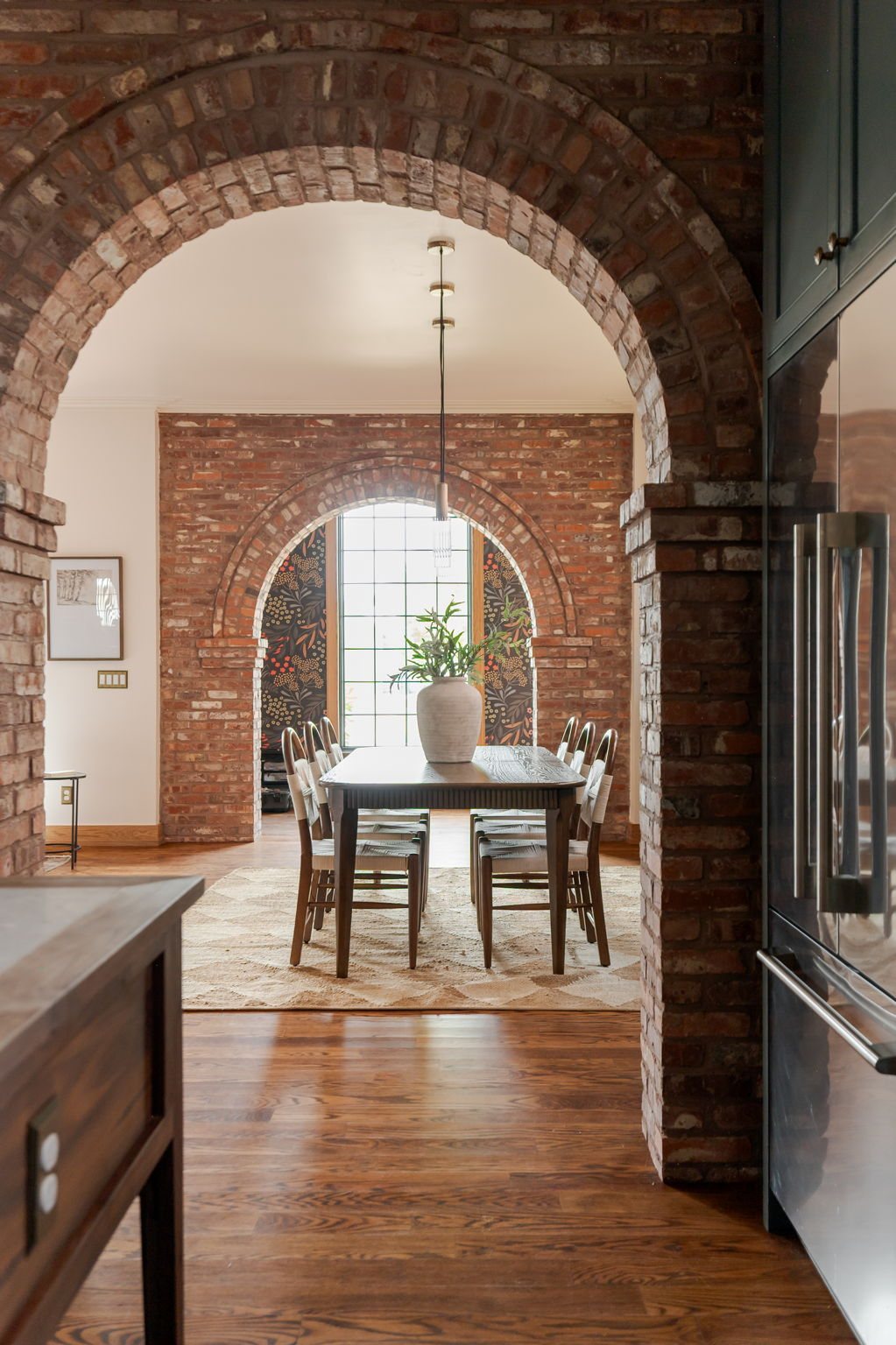 Nested brick arches — the foreground arch frames a second arched window beyond, with a wallpapered feature wall visible through the opening.