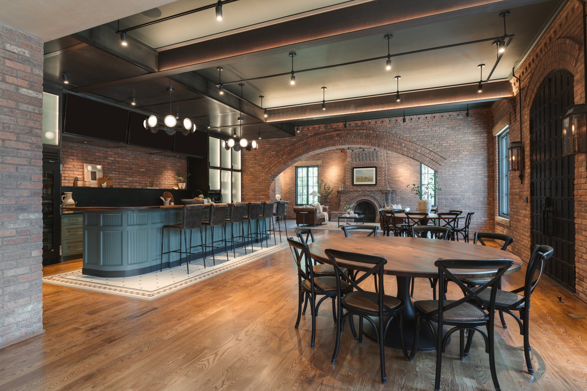 Restaurant interior at Selah — brick walls, a vaulted brick-arch fireplace, exposed ductwork overhead, and bistro seating around dark round tables.