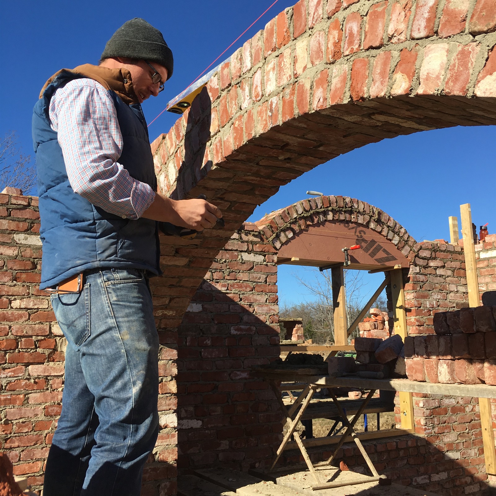 Austin laying brick by hand on a job site — close, hands-on work.