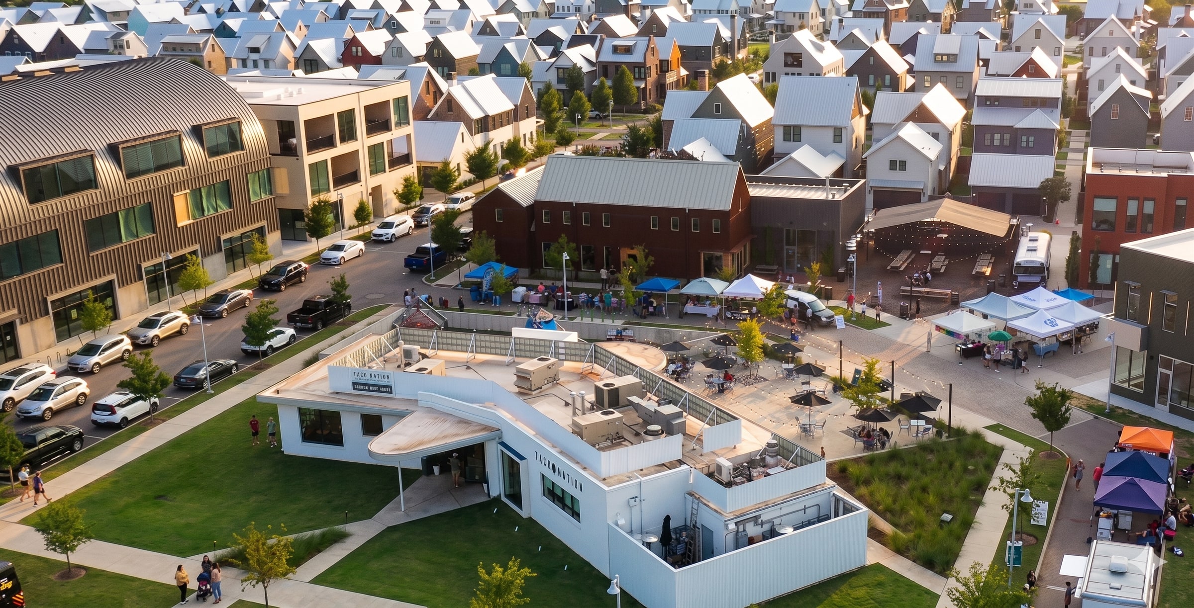 Aerial view of Wheeler District in Oklahoma City — brick homes around a market plaza with tents and a green, the walkable neighborhood that hosts the workshop.